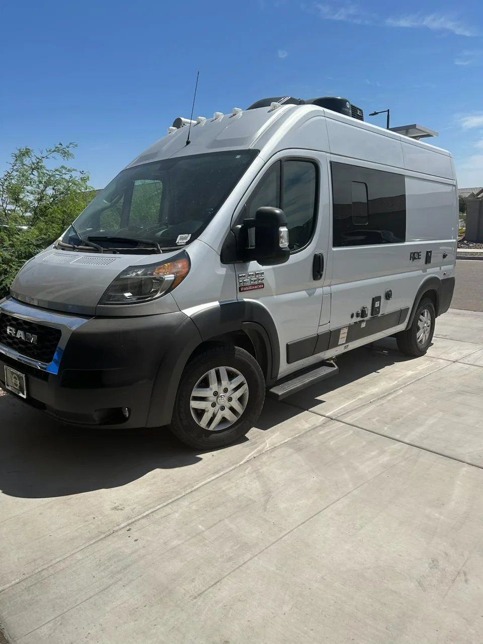 Ram ProMaster camper van parked in a driveway ahead of transport pickup