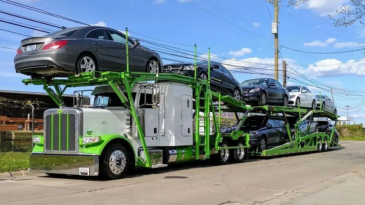 White and green Peterbilt car carrier loaded with Mercedes-Benz sedans