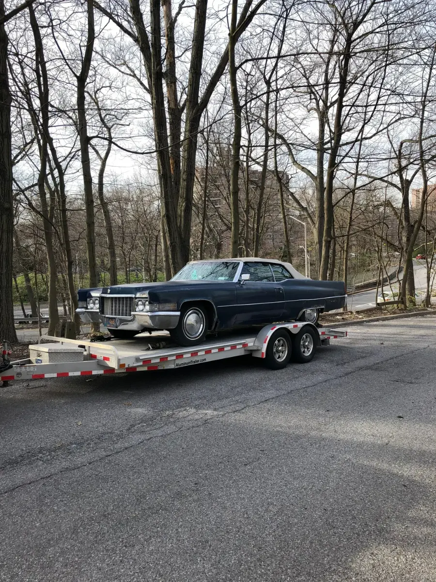 Vintage Cadillac DeVille convertible secured on an open aluminum car trailer