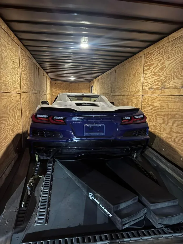 Chevrolet Corvette C8 loaded into a wood-lined enclosed car trailer with low-profile ramps