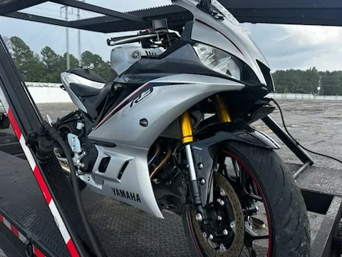 Silver Yamaha R3 sport bike strapped down on a motorcycle transport trailer