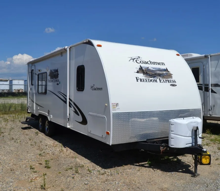Coachmen Freedom Express travel trailer on a gravel lot, ready for RV transport pickup