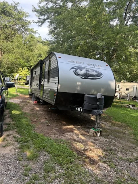 Grey Wolf travel trailer parked at a wooded campsite before RV transport